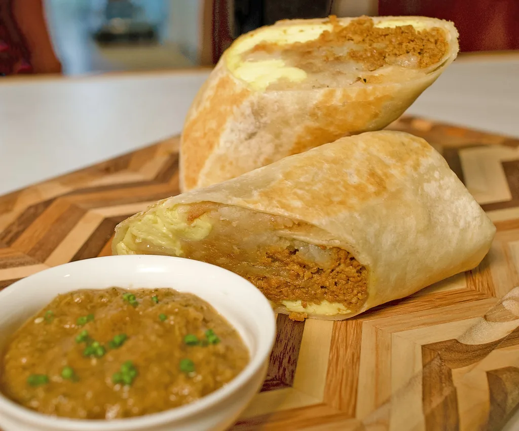 Breakfast burrito cut in half showing chorizo, scrambled egg and hashbrowns, with a side of salsa