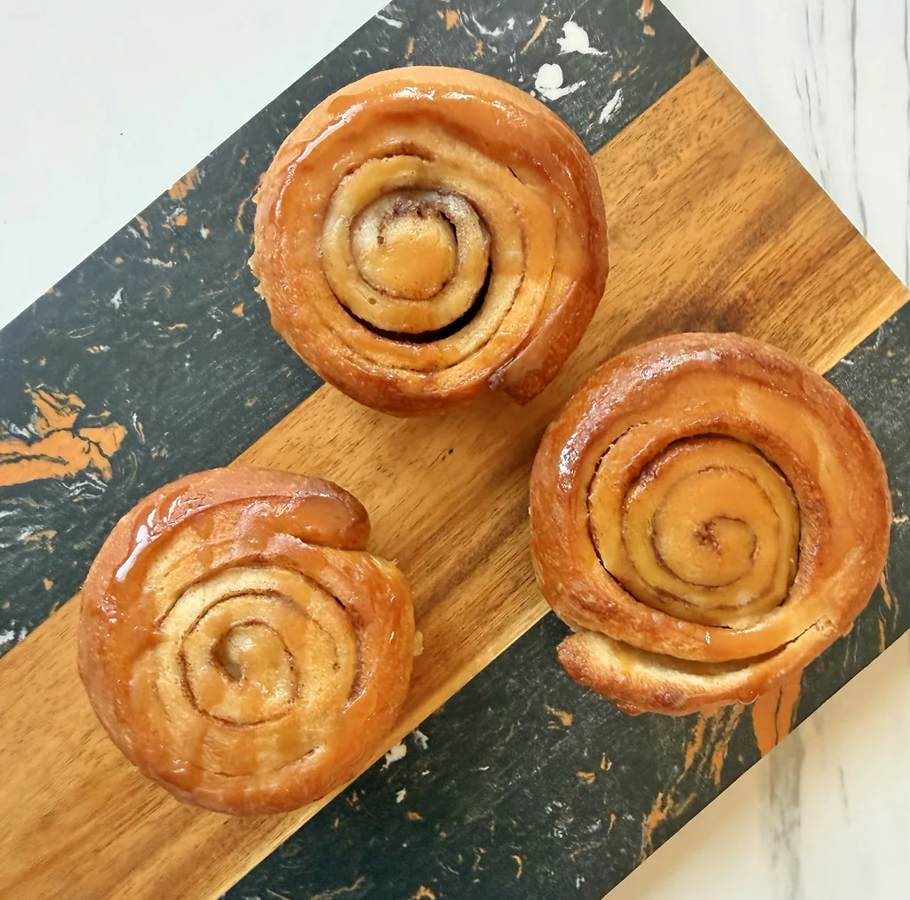 Three spiral brioche sticky buns on a serving board