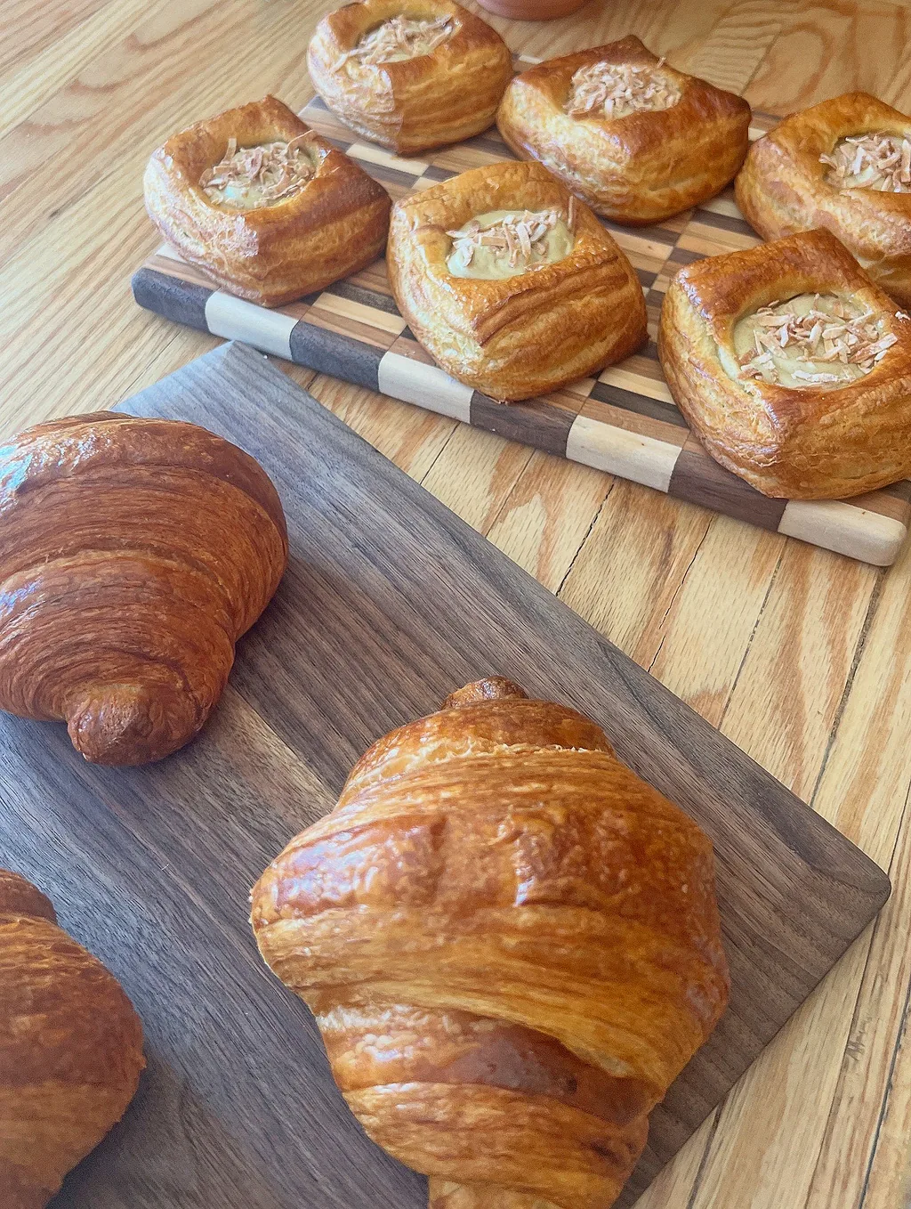 Croissants and almond danishes on wooden boards