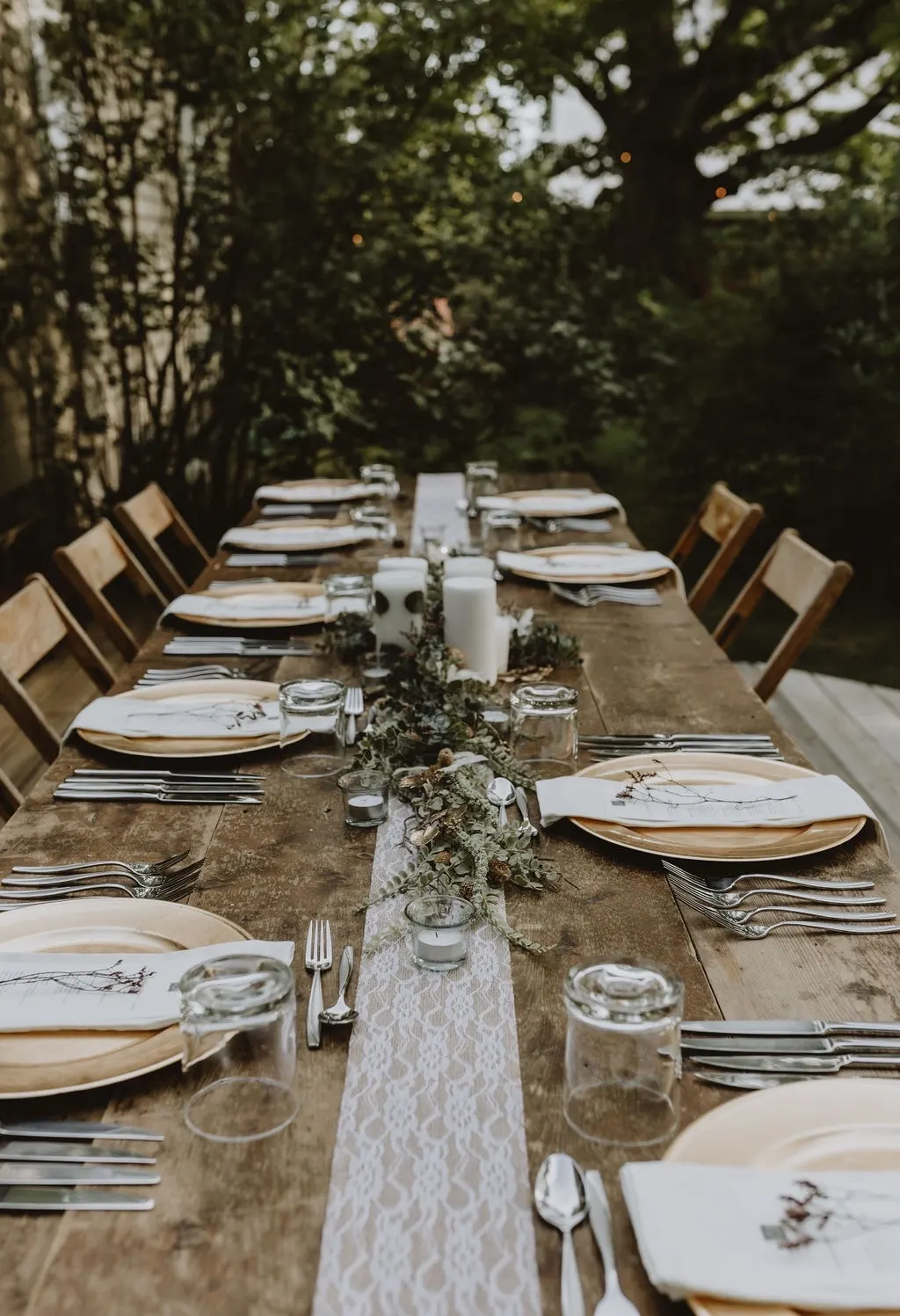 A garden table set with gold chargers and a greenery runner
