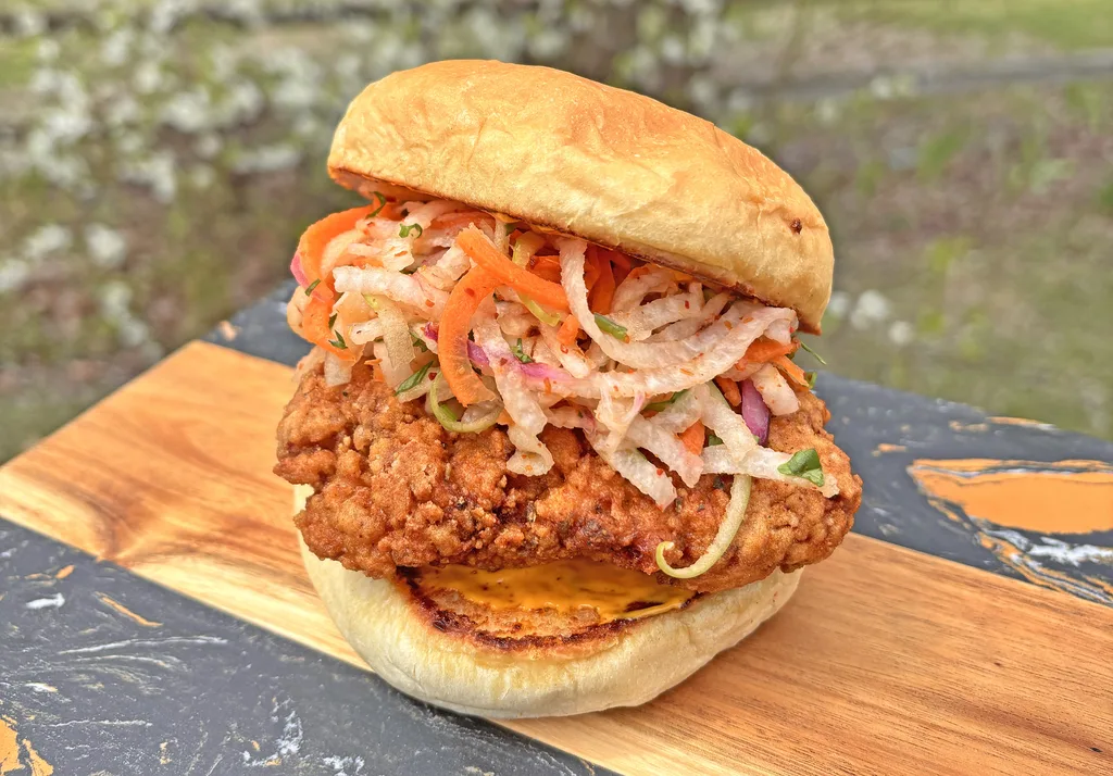 Crispy fried chicken thigh sandwich topped with jicama slaw and smokey aioli on a toasted bun
