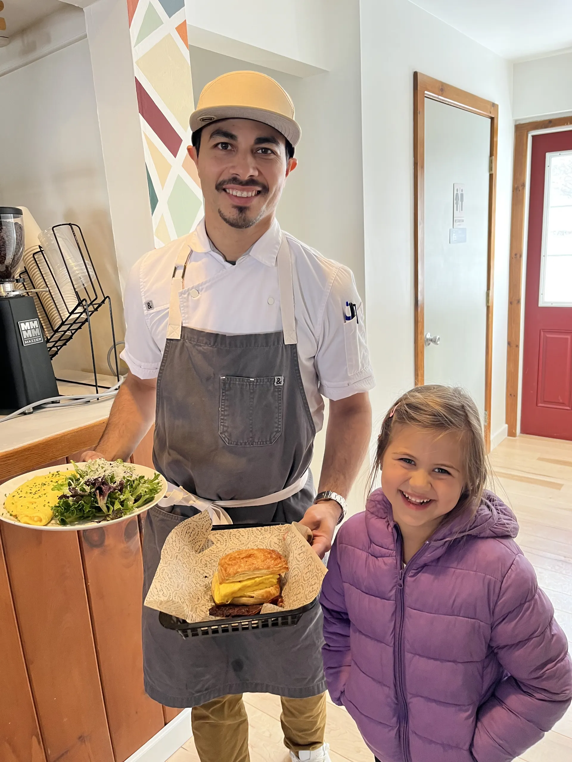 Chef Miguel Calderon carrying an omelette and a breakfast sandwich out to a young guest