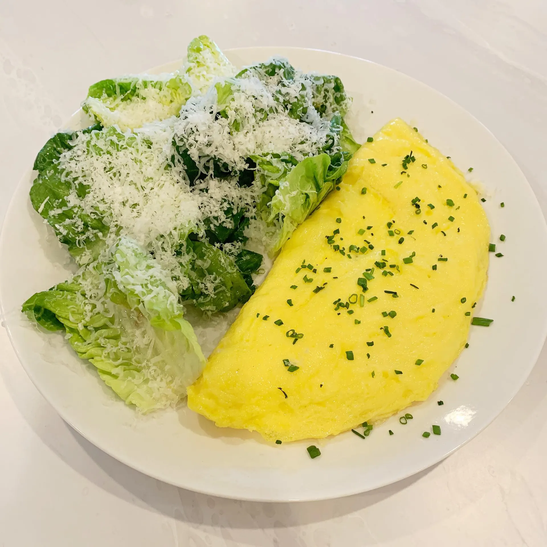 A folded omelette served with a side of greens