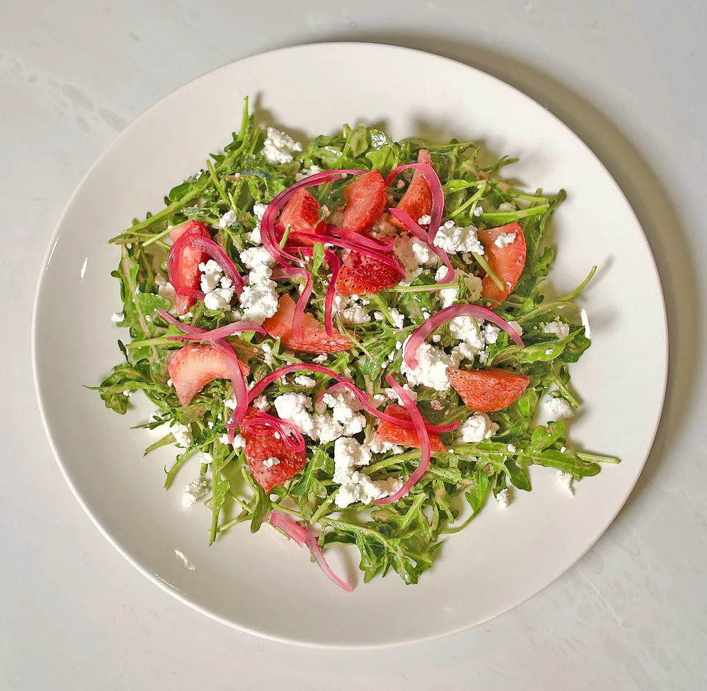 Arugula salad with sliced strawberries, goat cheese and marinated red onion